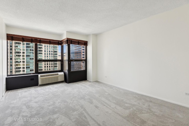 carpeted spare room featuring a wall unit AC and a textured ceiling