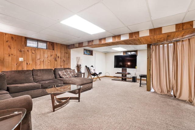 carpeted living room with a paneled ceiling and wood walls