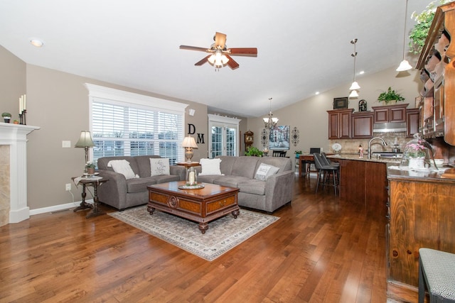 living room featuring dark hardwood / wood-style floors, high vaulted ceiling, a fireplace, and ceiling fan with notable chandelier