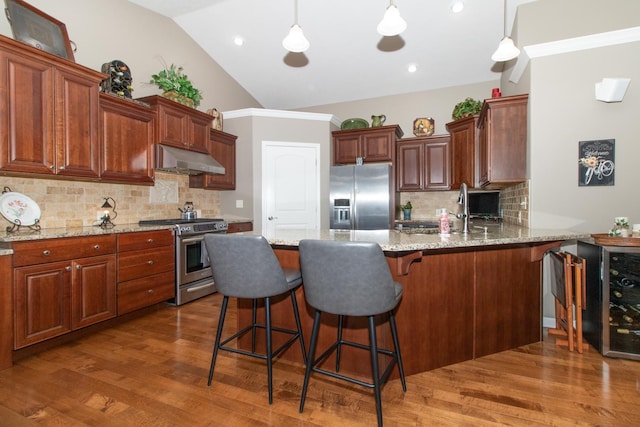 kitchen featuring sink, light stone counters, decorative light fixtures, appliances with stainless steel finishes, and kitchen peninsula