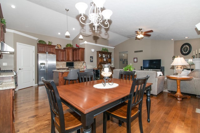 dining room featuring ceiling fan with notable chandelier, dark hardwood / wood-style flooring, and vaulted ceiling