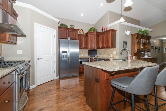 kitchen with sink, light stone countertops, a breakfast bar, and appliances with stainless steel finishes