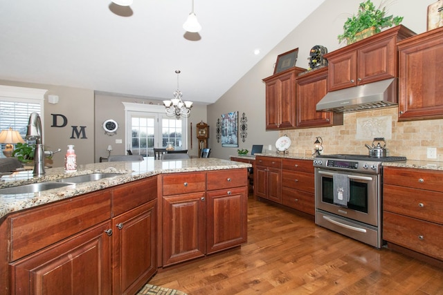 kitchen featuring sink, dark hardwood / wood-style floors, stainless steel stove, pendant lighting, and light stone countertops