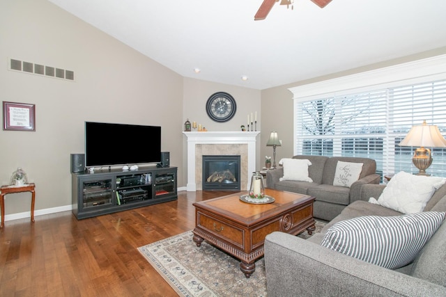 living room featuring ceiling fan, lofted ceiling, dark hardwood / wood-style flooring, and a tiled fireplace