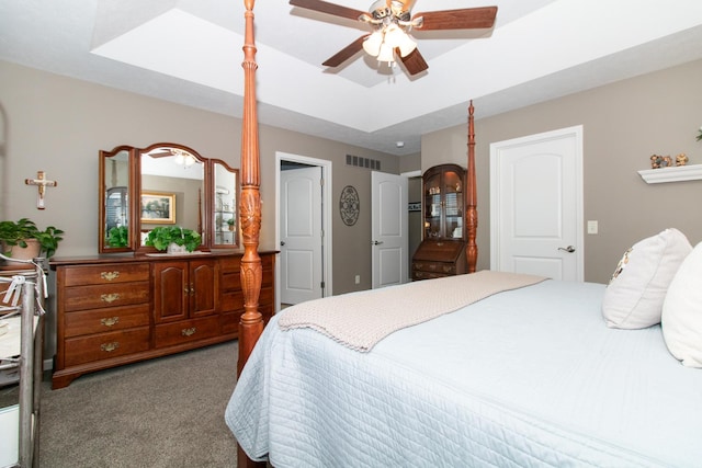 bedroom with ceiling fan, a tray ceiling, and light carpet