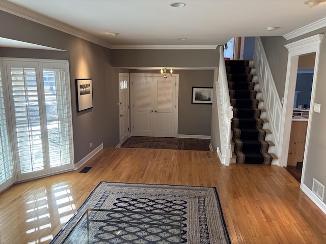 foyer featuring wood-type flooring, crown molding, and a notable chandelier