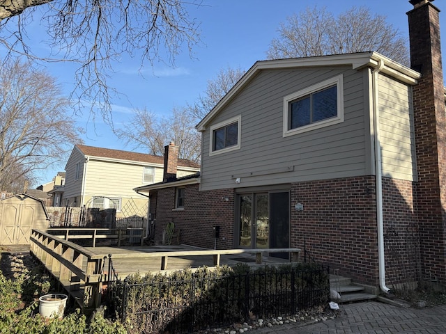 back of house with a wooden deck and a shed