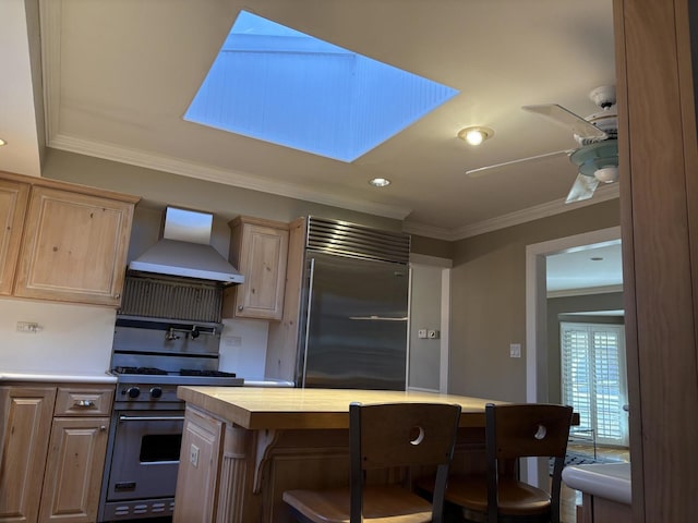 kitchen featuring a skylight, high quality appliances, wall chimney exhaust hood, and ornamental molding