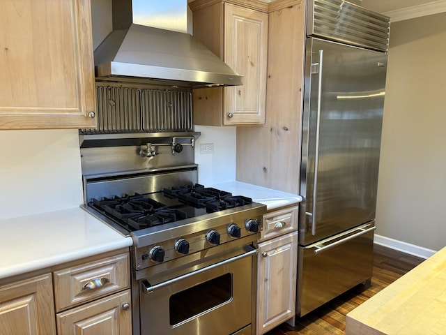 kitchen featuring light brown cabinets, dark hardwood / wood-style flooring, high quality appliances, and wall chimney range hood