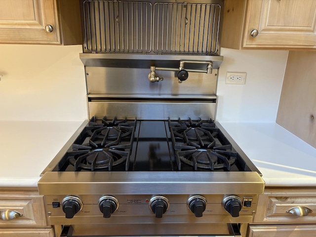 interior details with stainless steel gas stove and light brown cabinetry