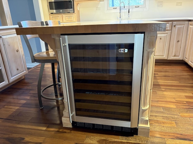 bar featuring stainless steel microwave, beverage cooler, dark hardwood / wood-style floors, and sink