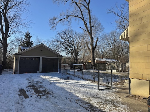 snowy yard with a garage and an outdoor structure