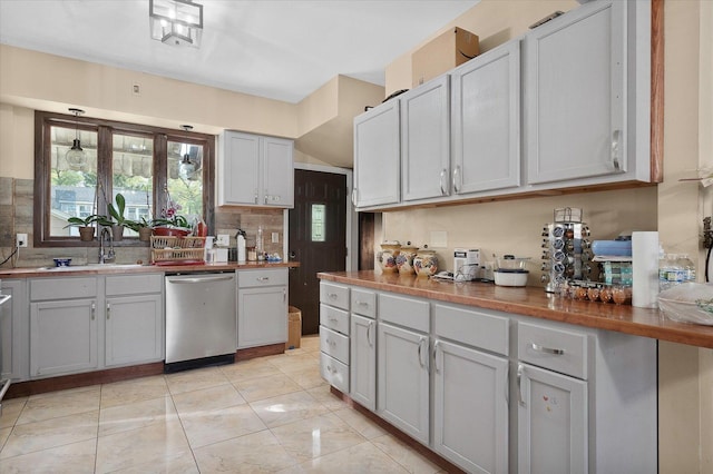 kitchen with butcher block counters, sink, tasteful backsplash, stainless steel dishwasher, and gray cabinets