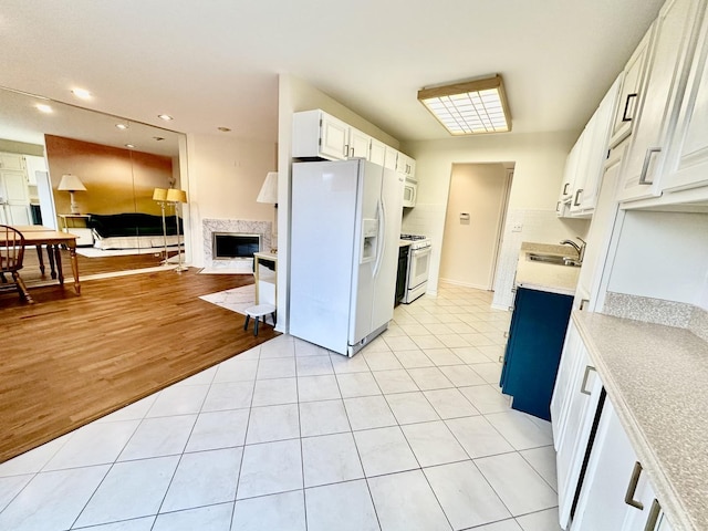 kitchen featuring white cabinets, light tile patterned floors, white appliances, and sink