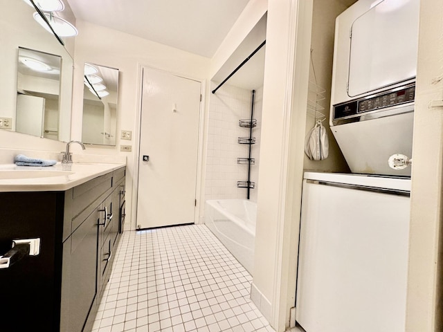 bathroom featuring tile patterned floors, stacked washer / drying machine, tiled shower / bath, and vanity