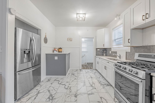 kitchen featuring backsplash, white cabinetry, sink, and appliances with stainless steel finishes