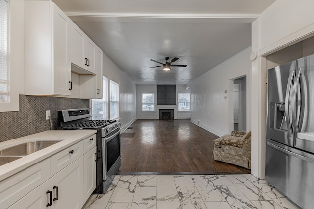 kitchen with appliances with stainless steel finishes, tasteful backsplash, white cabinetry, and ceiling fan