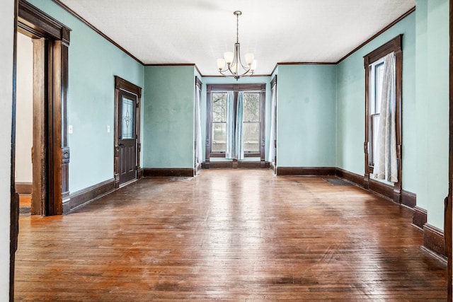 spare room featuring ornamental molding, dark hardwood / wood-style flooring, and a notable chandelier