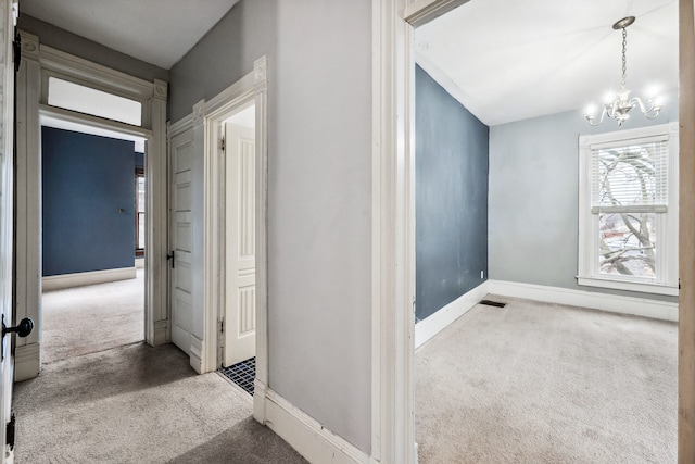 hallway with carpet and an inviting chandelier