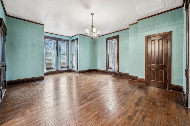 empty room featuring dark hardwood / wood-style flooring, ornamental molding, and a chandelier