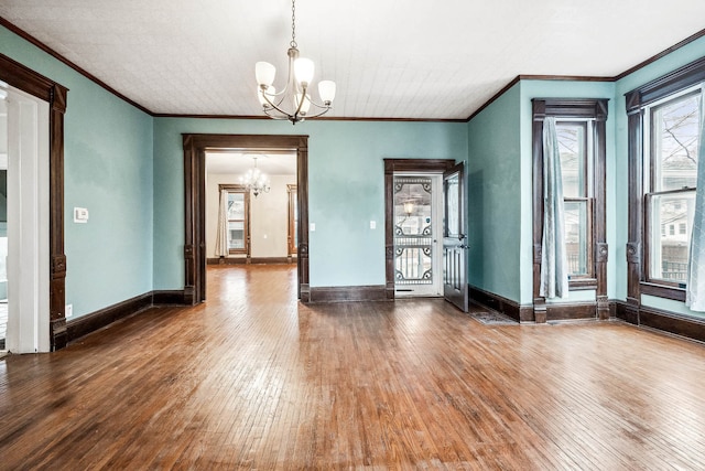 unfurnished dining area with wood-type flooring, ornamental molding, and a chandelier