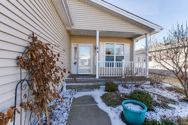 snow covered property entrance featuring a porch