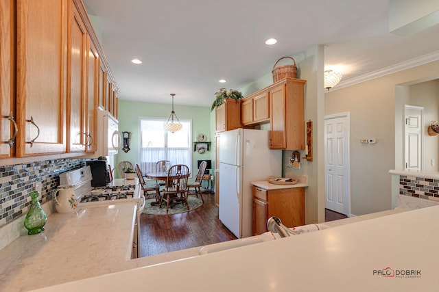 kitchen featuring white appliances, crown molding, dark wood-type flooring, decorative light fixtures, and backsplash