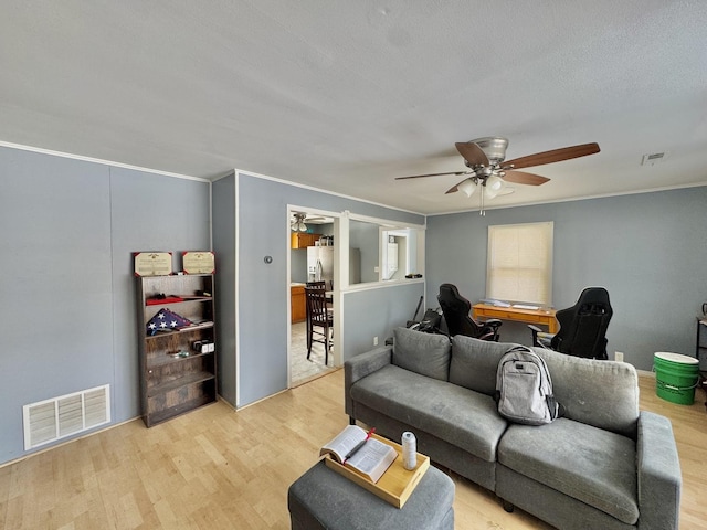 living room with ceiling fan, crown molding, and light hardwood / wood-style flooring