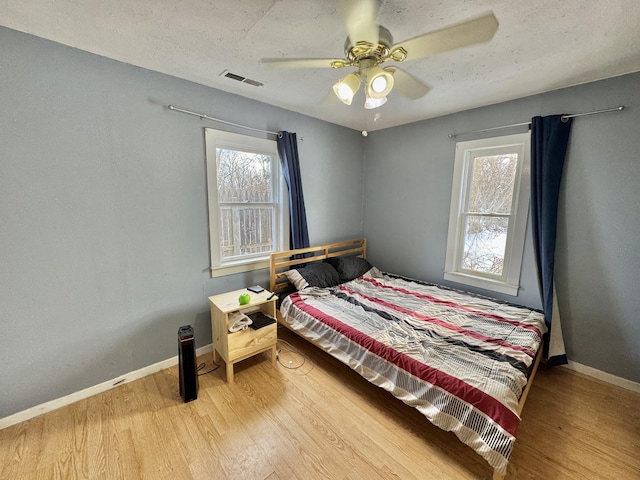 bedroom featuring hardwood / wood-style floors, ceiling fan, and a textured ceiling