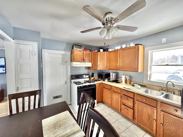 kitchen featuring light tile patterned floors, ceiling fan, white range with gas cooktop, and sink