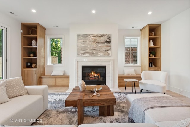 living area featuring a wealth of natural light, light hardwood / wood-style floors, and a tile fireplace