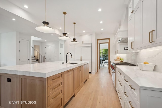 kitchen featuring white cabinetry, hanging light fixtures, a large island, and sink