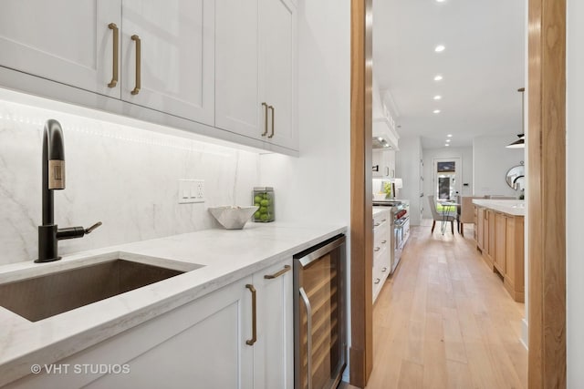 bar with light stone countertops, white cabinets, and beverage cooler