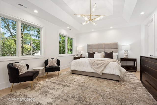 bedroom featuring a chandelier, wood-type flooring, and a raised ceiling