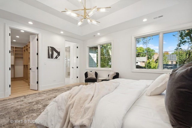 bedroom featuring a closet, a spacious closet, multiple windows, and an inviting chandelier