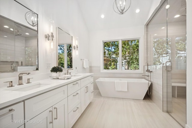 bathroom featuring vanity, tile walls, independent shower and bath, and a chandelier