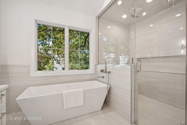 bathroom with shower with separate bathtub, vanity, tile walls, and a healthy amount of sunlight