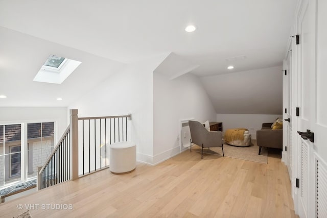 sitting room with light hardwood / wood-style flooring and lofted ceiling with skylight