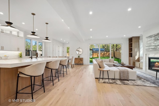 living room featuring light wood-type flooring, a healthy amount of sunlight, and sink