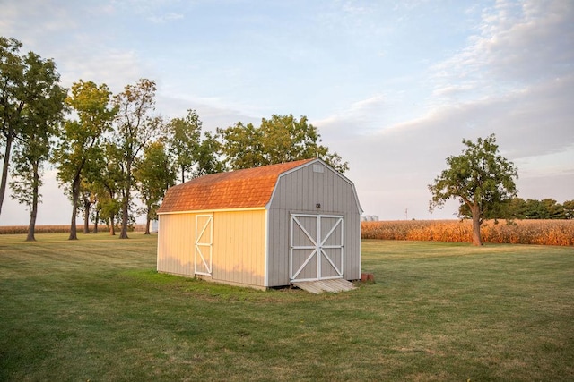 view of outbuilding featuring a rural view and a lawn