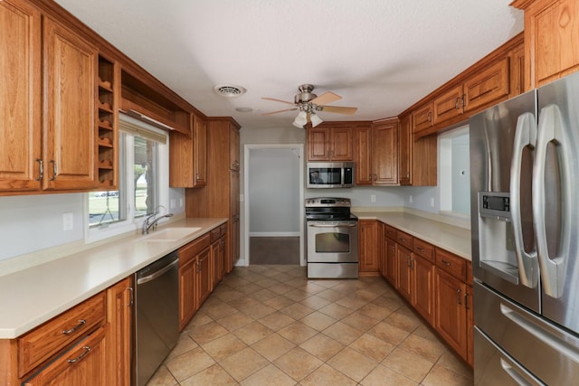 kitchen with sink, appliances with stainless steel finishes, light tile patterned flooring, and ceiling fan