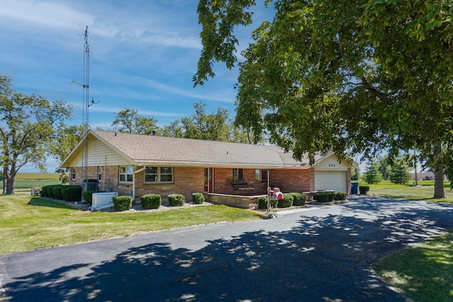 ranch-style home with a garage, cooling unit, and a front yard