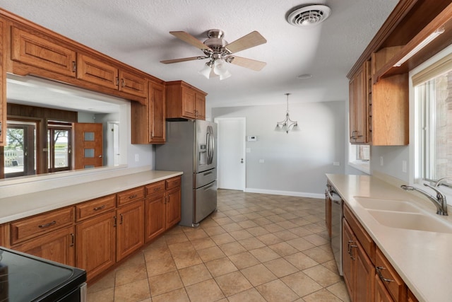 kitchen featuring appliances with stainless steel finishes, a textured ceiling, ceiling fan, pendant lighting, and sink