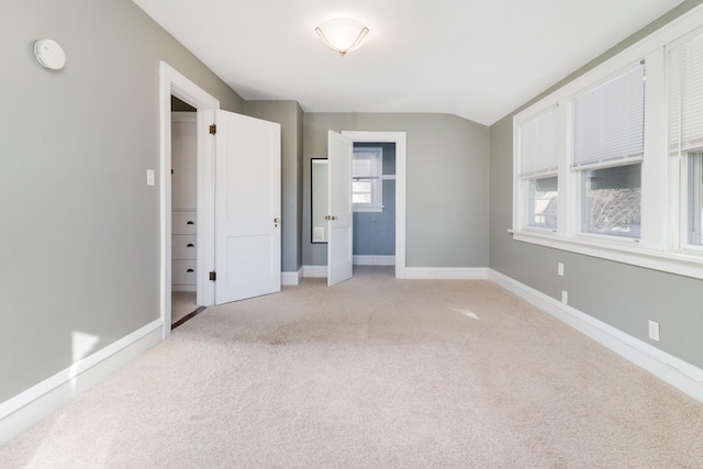 unfurnished bedroom with vaulted ceiling and light colored carpet