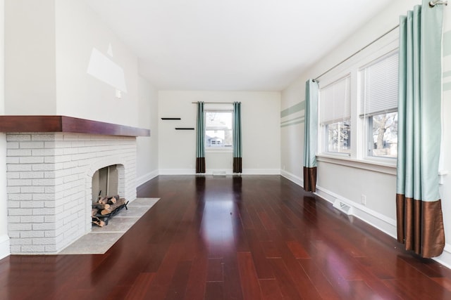 unfurnished living room with hardwood / wood-style flooring and a brick fireplace