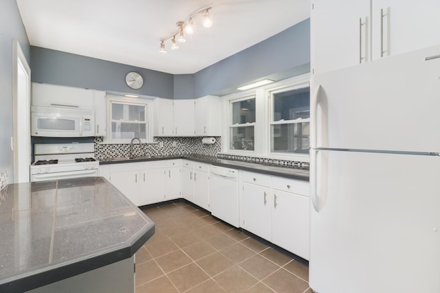 kitchen with sink, white appliances, dark tile patterned floors, white cabinetry, and tasteful backsplash