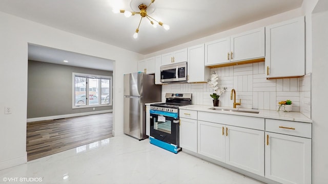 kitchen with sink, appliances with stainless steel finishes, tasteful backsplash, a notable chandelier, and white cabinetry