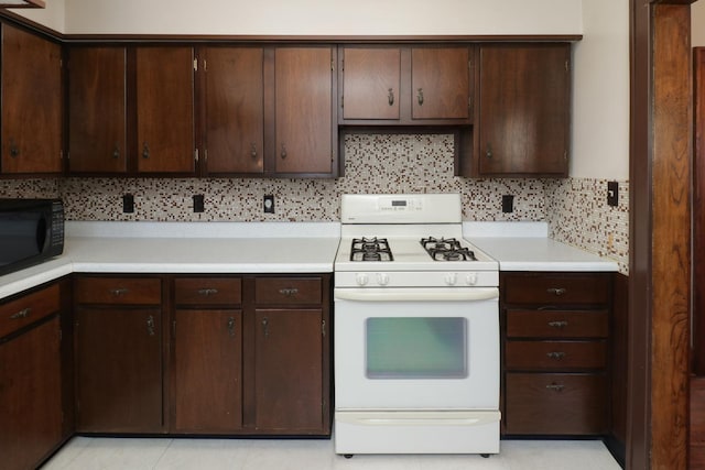 kitchen with tasteful backsplash, white gas stove, and dark brown cabinetry