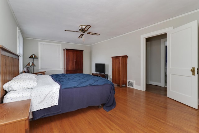 bedroom with ceiling fan, ornamental molding, and hardwood / wood-style floors