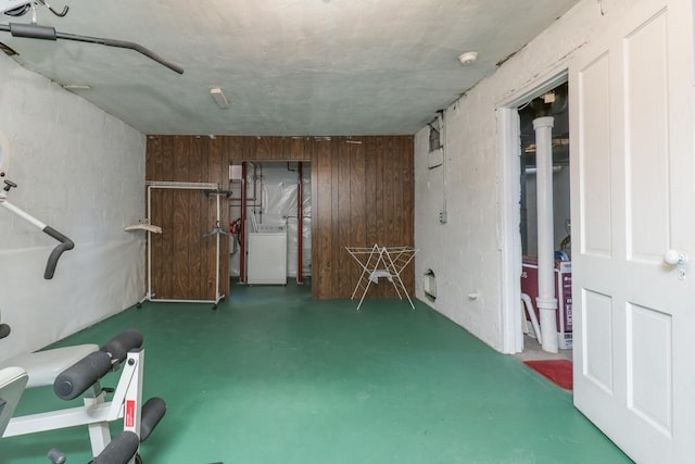 miscellaneous room with concrete flooring, washer / dryer, and wood walls